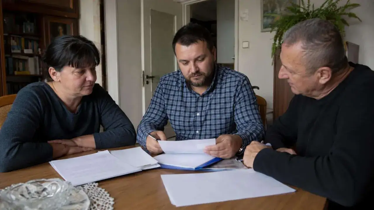 Rodzina omawia dokumenty. Jeden ze spadkobierców korzysta z mieszkania, analizując papiery przy stole.