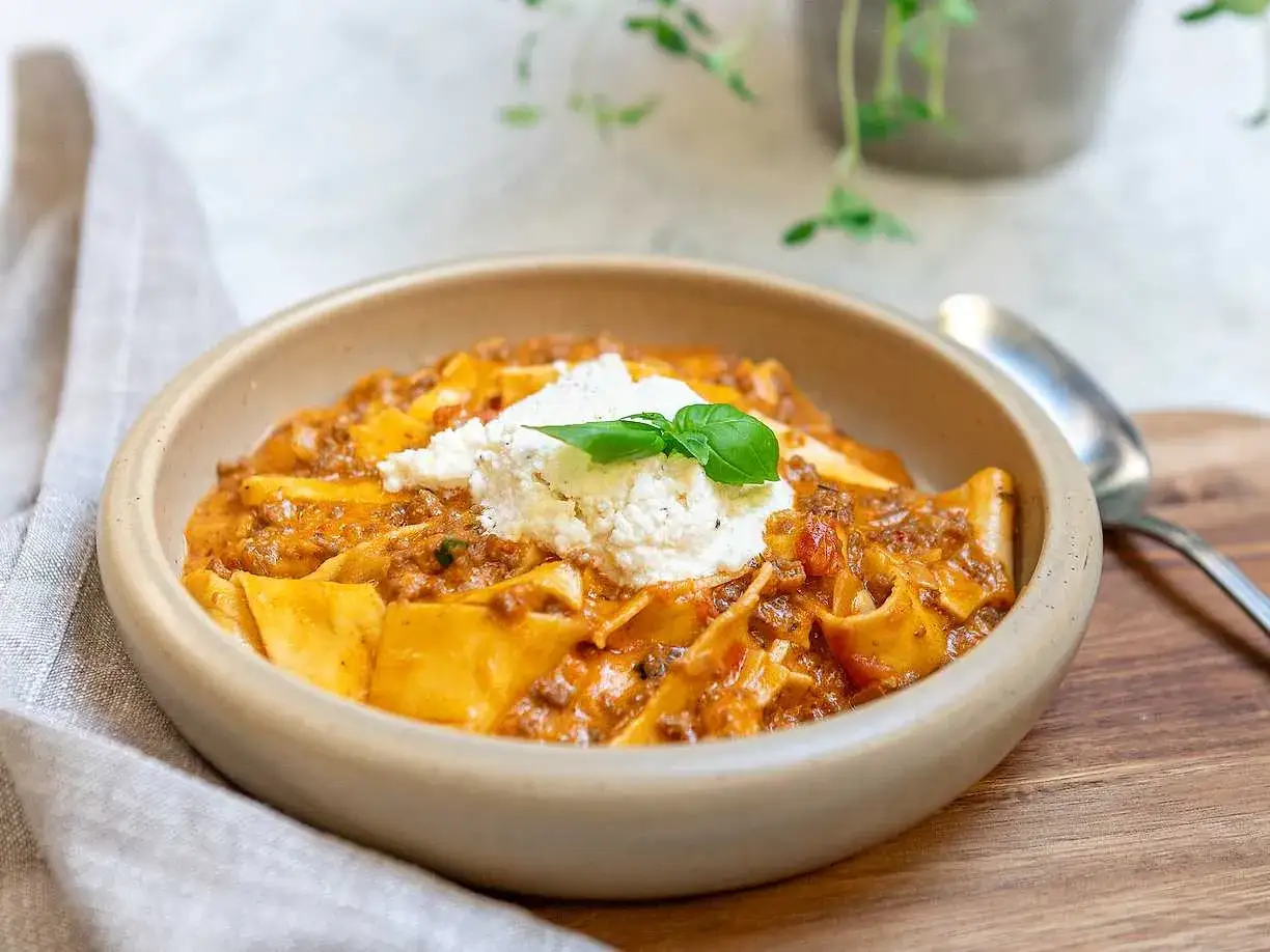 En kr&auml;mig lasagne soppa med breda pastablad, k&ouml;ttf&auml;rss&aring;s och en klick ricotta, toppad med basilika.