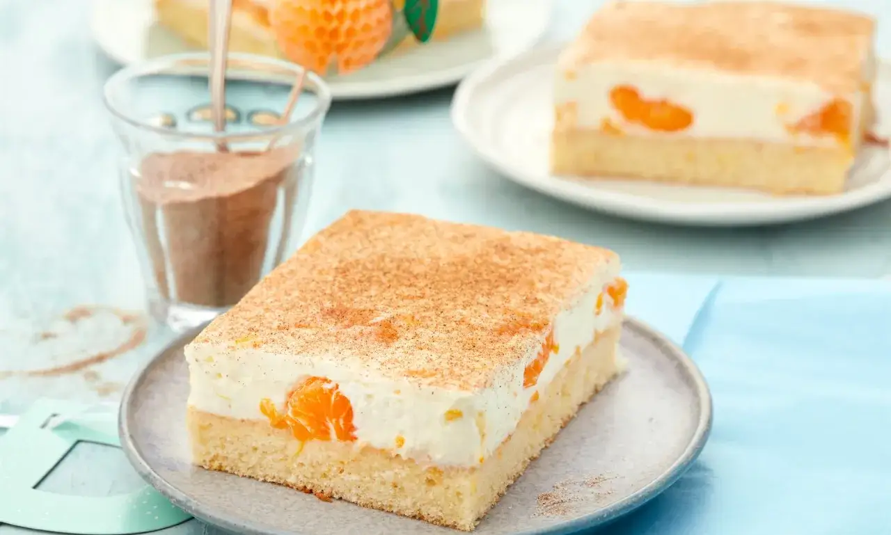 Ein saftiger Fantakuchen vom Blech, belegt mit Mandarinen und einer cremigen Schicht, bestreut mit Zimt.