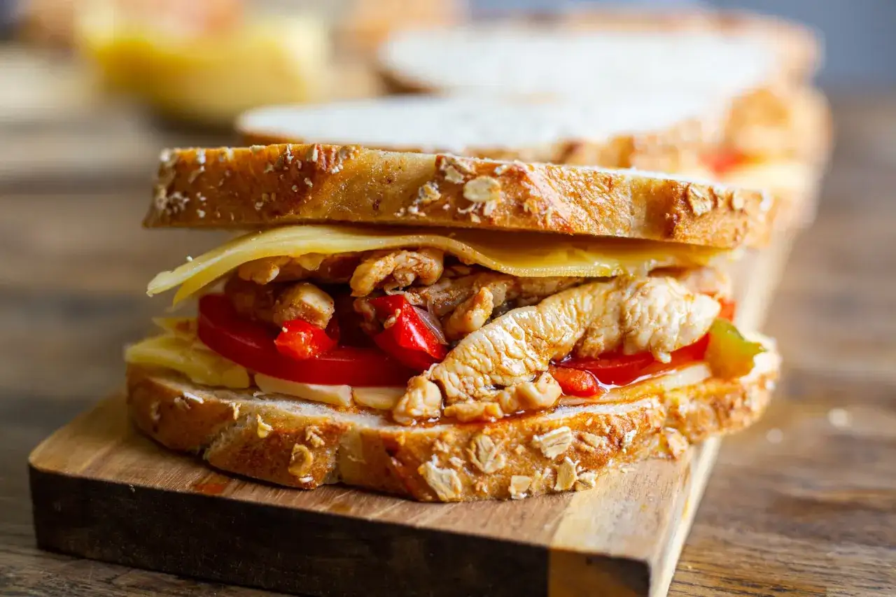 En saftig sandwich med smulad kyckling, ost och tomat p&aring; grovt br&ouml;d.
