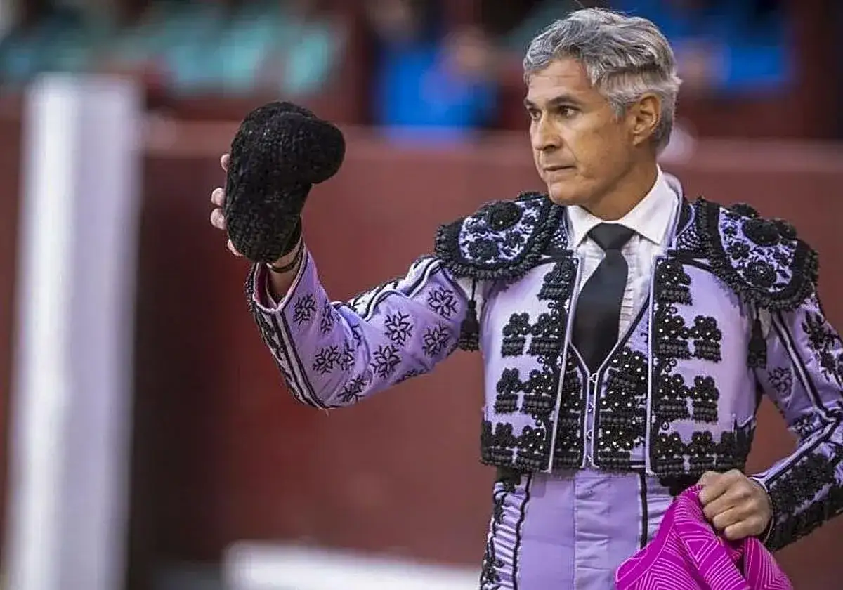 Torero con traje de luces morado, listo para el tercio de banderillas, sostiene una montera negra.