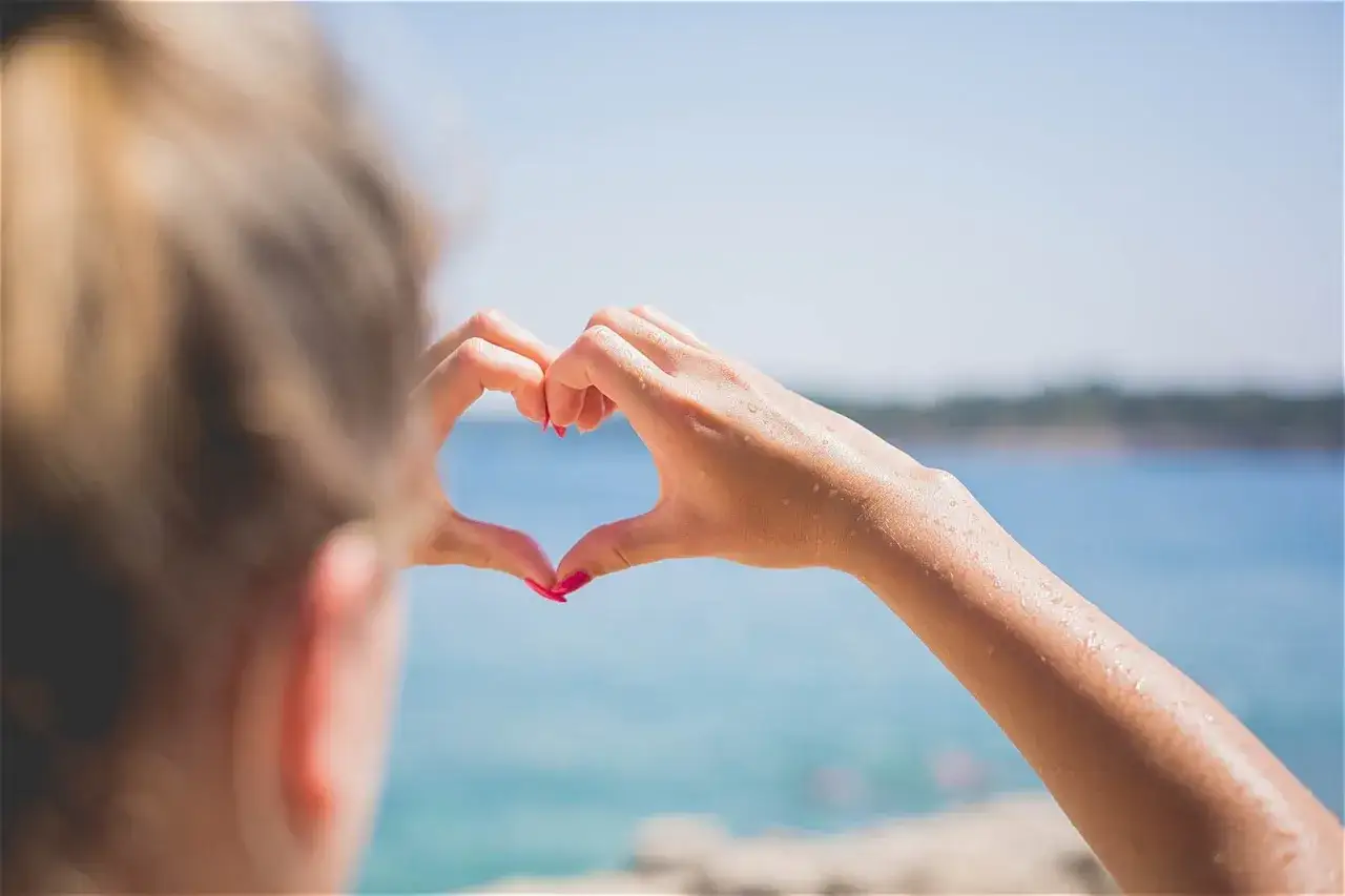 Maintenant, après le premier rendez-vous, elle forme un cœur avec ses mains mouillées, regardant la mer.
