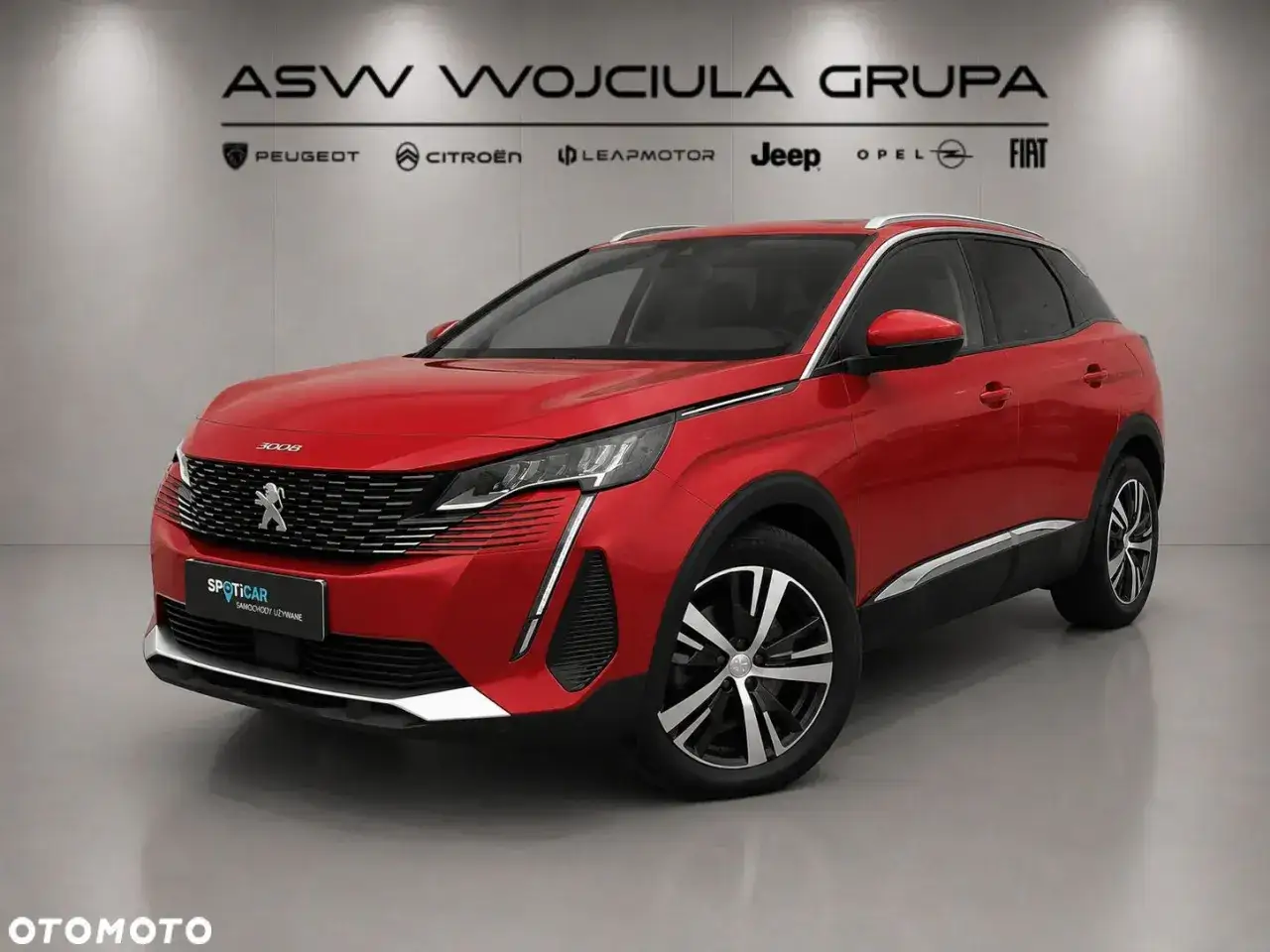 Czerwony Peugeot 3008, część grupy PSA, prezentuje się na tle salonu samochodowego.