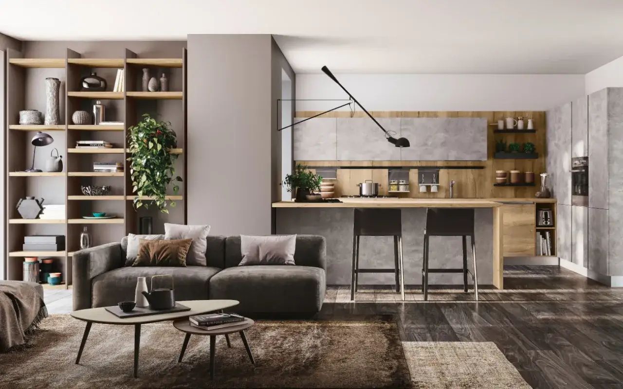 Elegante appartamento open space moderno con divano grigio, tavolini, libreria e cucina a vista con isola.