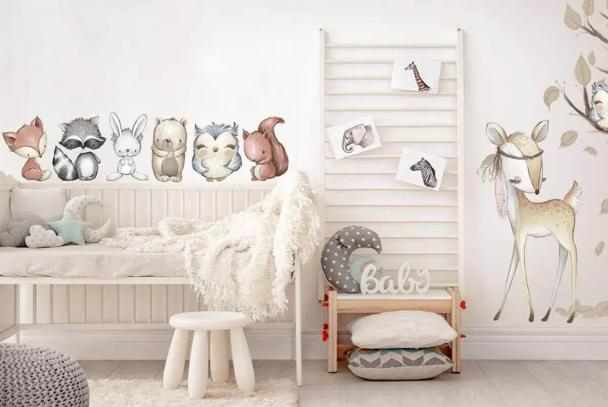 Adorables cuadros infantiles de animales del bosque y la sabana decoran una habitaci&oacute;n de beb&eacute; con cuna y peluches.