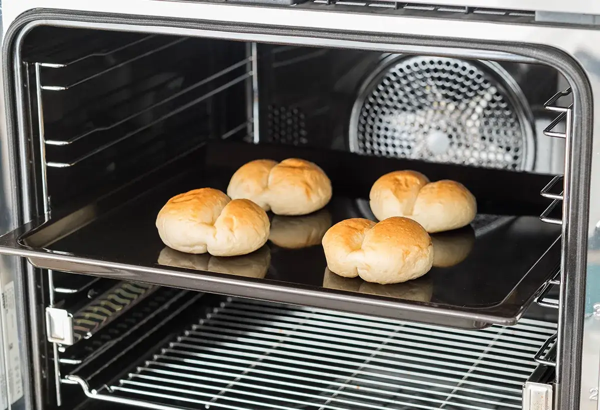 Cinq petits pains dor&eacute;s sur une plaque de cuisson dans un four. C'est une bonne id&eacute;e pour savoir qu'est-ce qu'un l&egrave;chefrite.