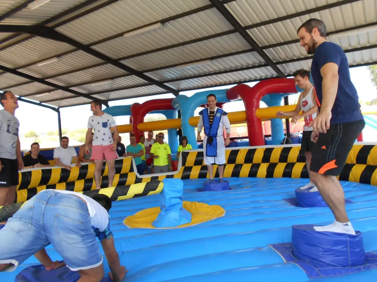 Hombres compiten en juegos inflables, parte de divertidos juegos para despedida de soltero.