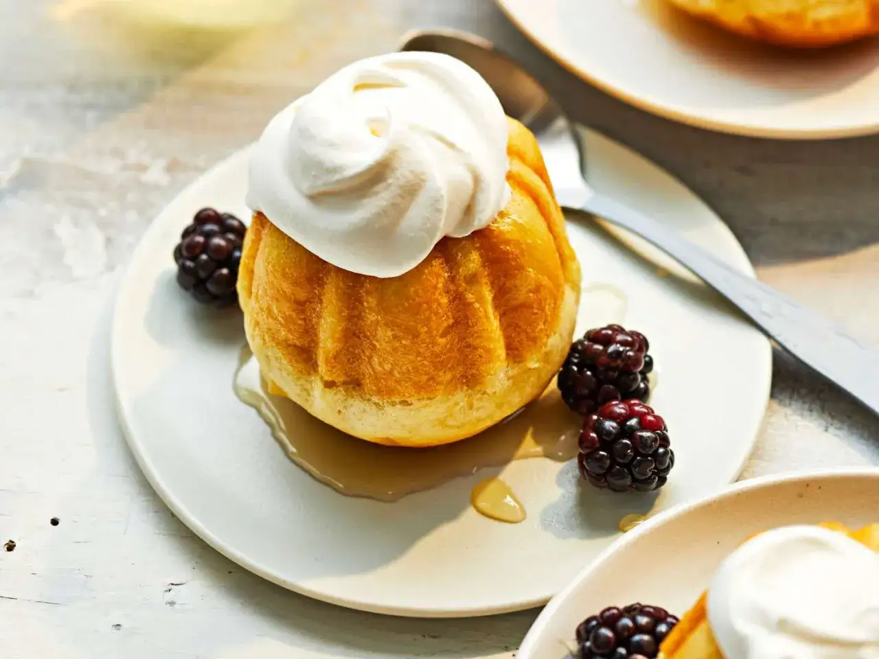 Un delicioso baba al ron, esponjoso y ba&ntilde;ado en alm&iacute;bar, coronado con crema batida y acompa&ntilde;ado de moras frescas.
