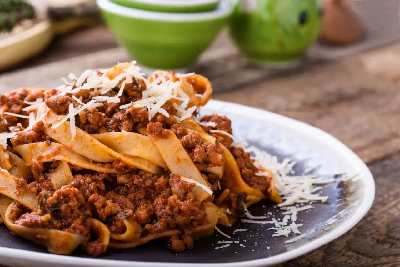 Pappardelle z bogatym sosem bolognese, posypane startym parmezanem. To pyszne mięso na spaghetti, które zachwyca smakiem.
