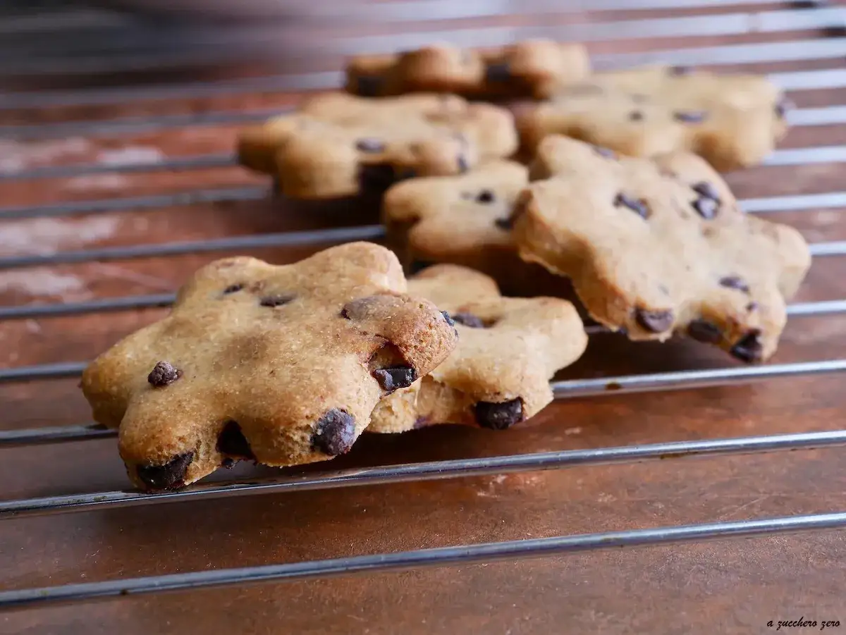Biscotti senza zucchero a forma di fiore con gocce di cioccolato, raffreddati su una griglia.