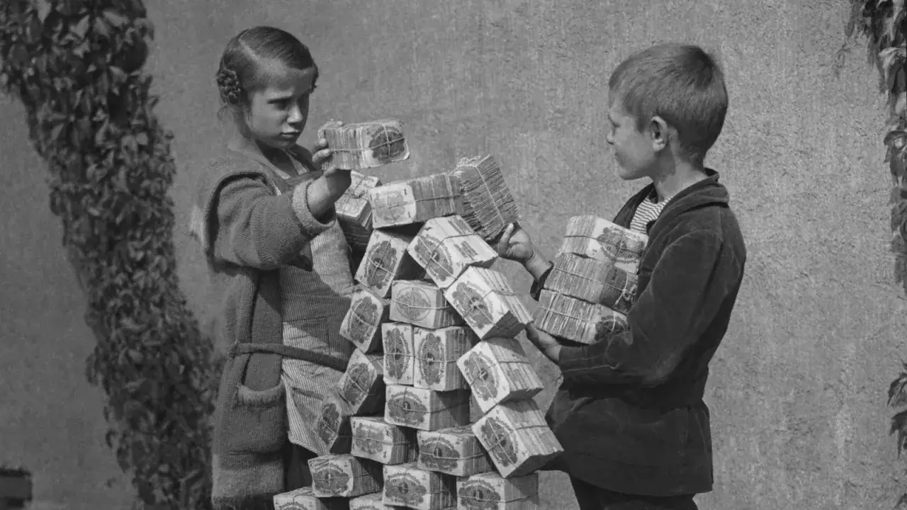 Kinder stapeln Bündel von Banknoten, ein Symbol der Hyperinflation 1923. Der Wert des Geldes schwindet, während die Berge wachsen.