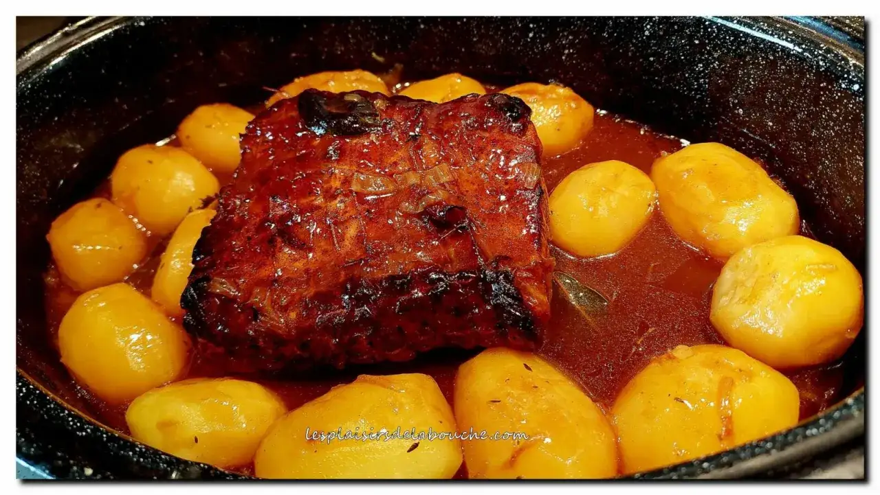 Un délicieux rôti de porc à la cocotte en sauce, entouré de pommes de terre dorées, prêt à être dégusté.