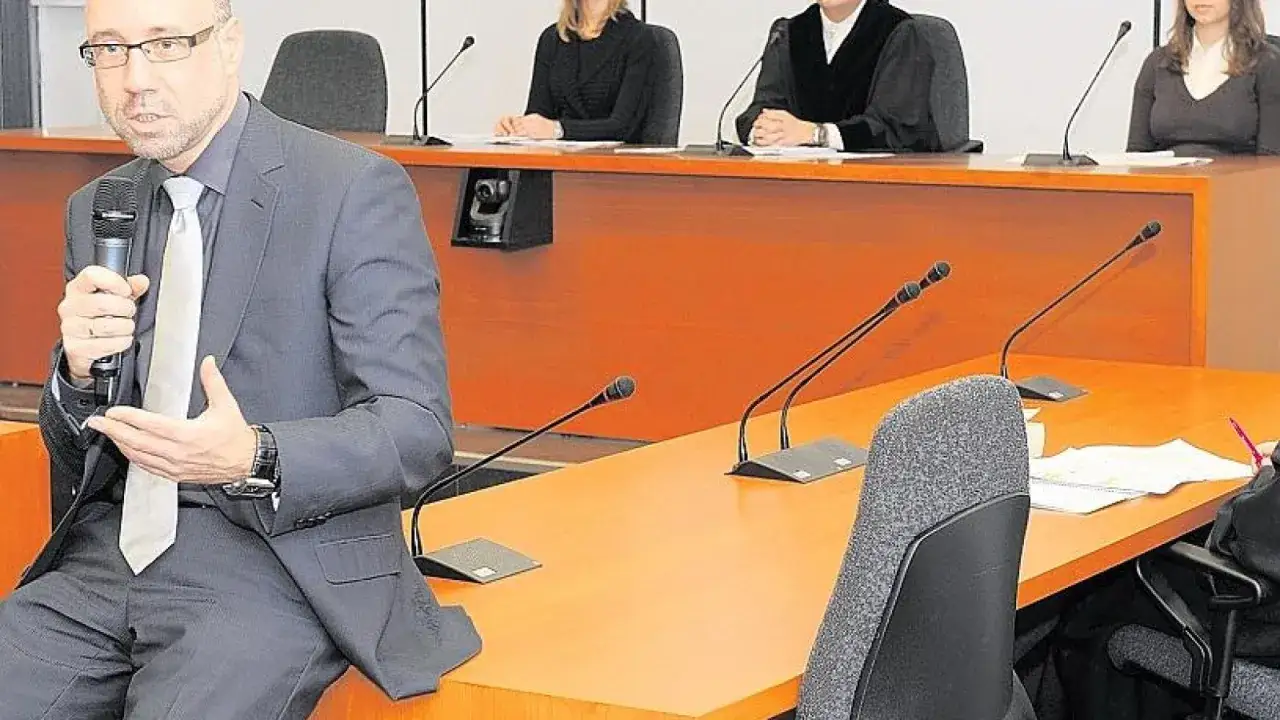 Mann spricht ins Mikrofon, im Hintergrund Richter und Zuh&ouml;rer bei einer Veranstaltung zur uni bochum jura.