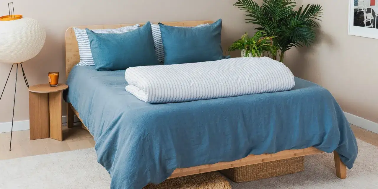 Ein gemütliches Bett mit blauem Bettbezug und gestreiftem Bettdeckenbezug. Was ist Bettbezug? Eine Hülle für die Decke, die sie sauber hält.
