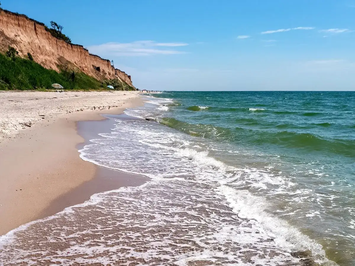 Piękna plaża w Sarbinowie nad morzem. Klify, zielona trawa i spokojne fale tworzą malowniczy krajobraz.