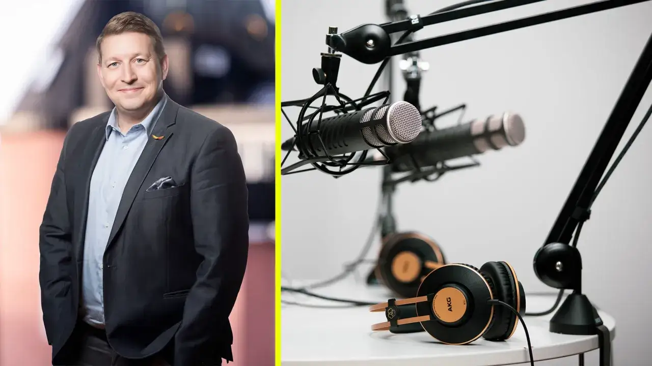 Man i kostym ler mot kameran, bredvid mikrofoner och hörlurar redo för podd ledarskap.