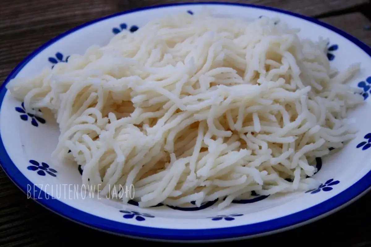 Gotowy do przygotowania makaron ryżowy na talerzu z niebieskimi kwiatkami. Proste i szybkie danie bezglutenowe.