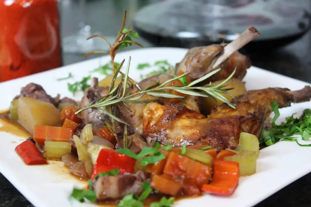 Leckerer Hasenbraten im Backofen, serviert mit Kartoffeln, Karotten und Paprika, garniert mit Rosmarin.