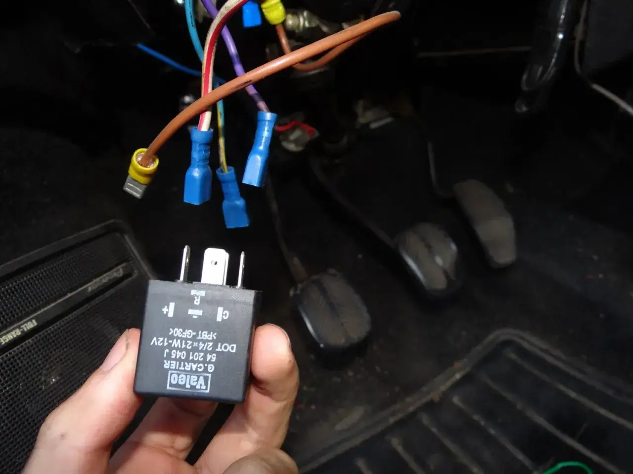 Main tenue, un relais Valeo pour clignotant fonctionne par intermittence. Des fils &eacute;lectriques sont connect&eacute;s sous le tableau de bord.
