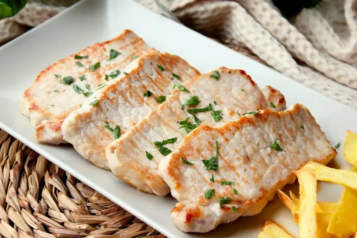 Cuatro filetes de lomo adobado, dorados y jugosos, espolvoreados con perejil fresco, acompañados de patatas fritas.