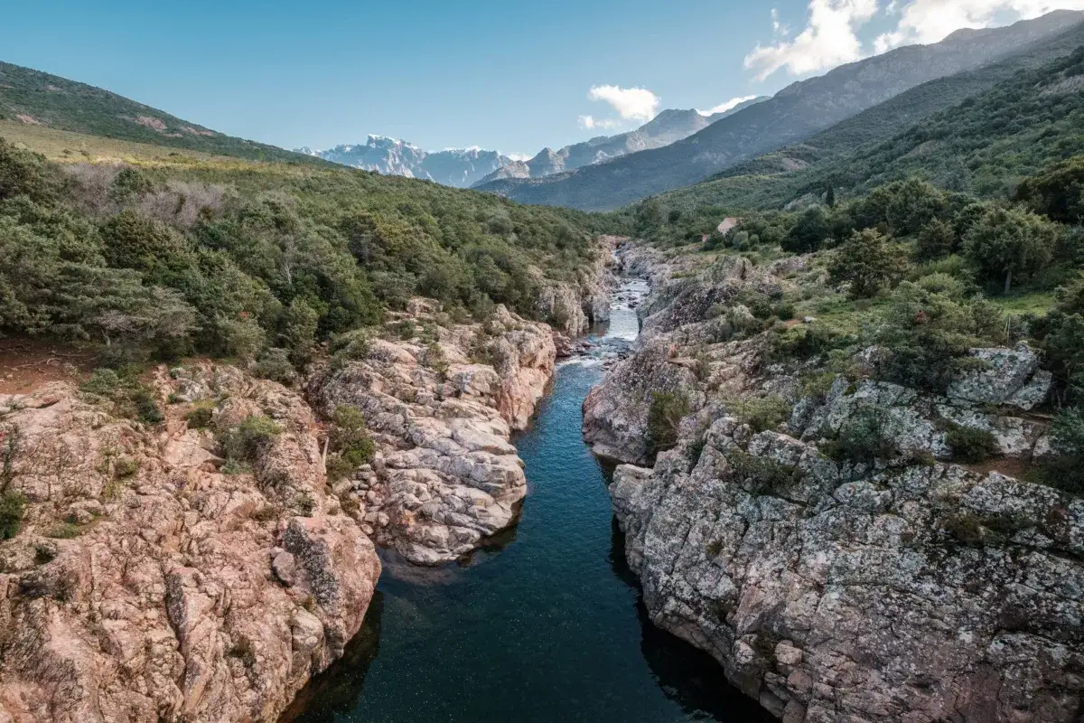 Un torrent serpente entre des rochers escarpés, traversant une vallée verdoyante. La **mare** au nord, avec sa **difficulté** naturelle, invite à l'aventure.