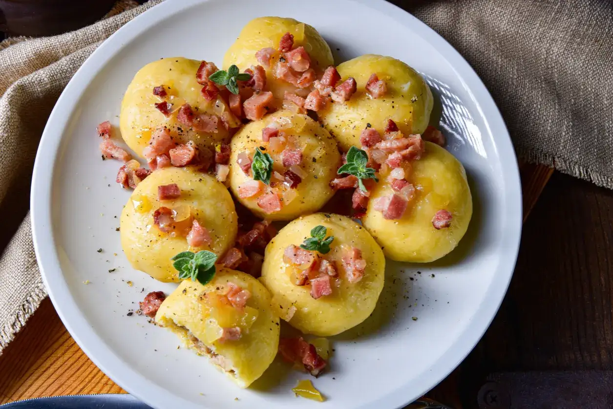 Pyzy ziemniaczane z mięsem, przepis babci. Pyszne, domowe kluski ziemniaczane z farszem mięsnym, okraszone skwarkami i cebulką.