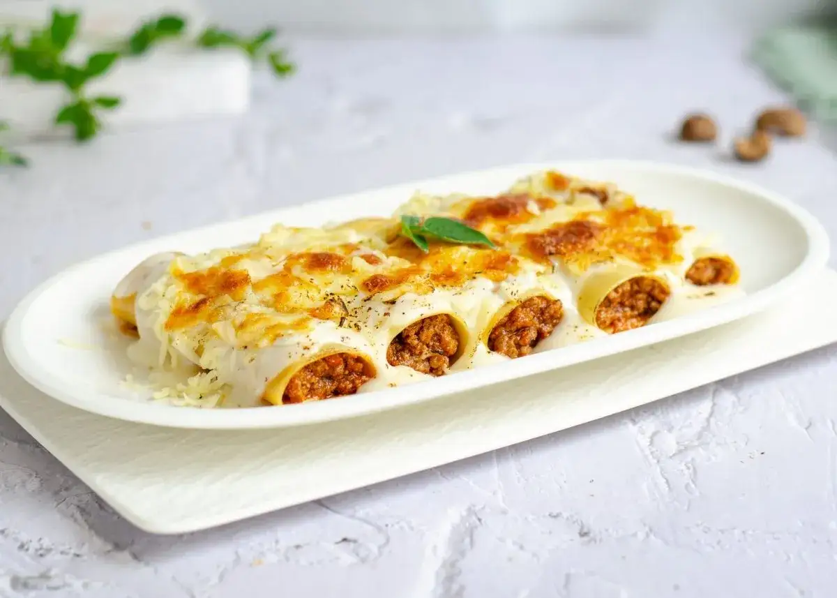 Canelones de carne gratinados con queso, cubiertos de bechamel y un toque de perejil. ¡Un plato casero irresistible!