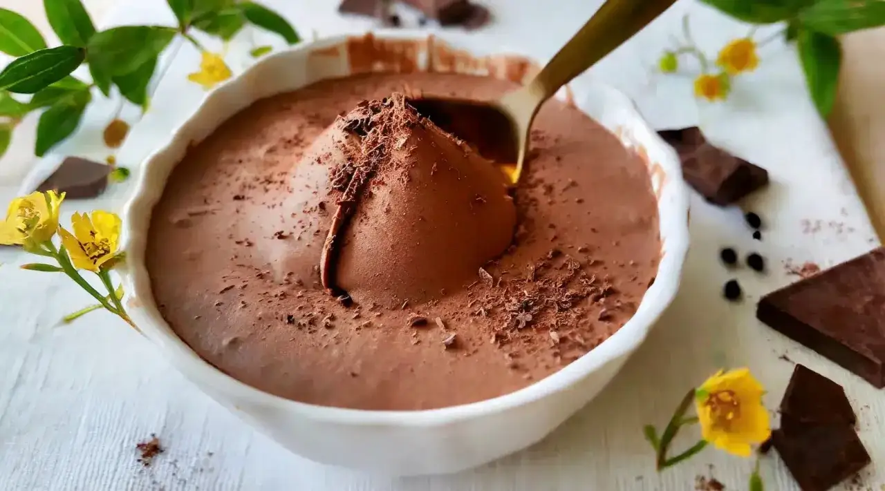 Une cuillère plonge dans une mousse au chocolat onctueuse, parsemée de copeaux. Une invitation à découvrir la recette mousse au chocolat à l'ancienne.