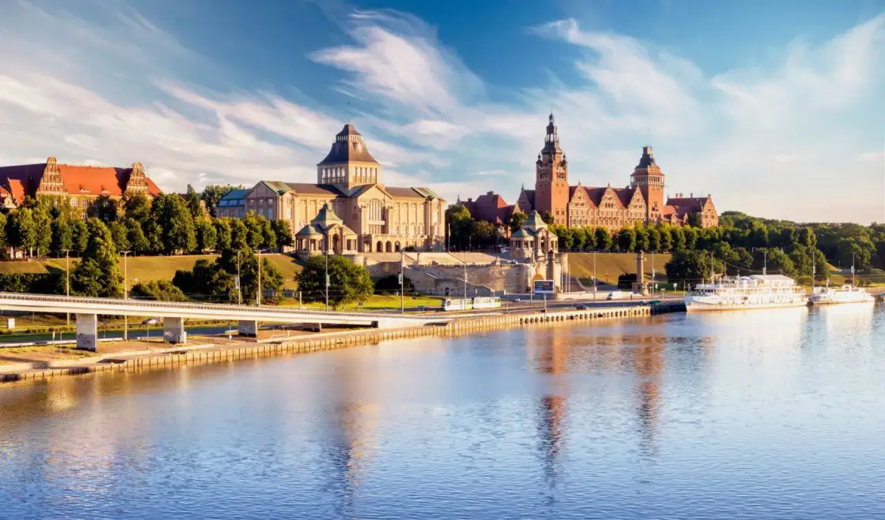 Widok na Wały Chrobrego w Szczecinie, idealne miejsce, by zobaczyć, co robić w Szczecinie. Statki, zabytkowe budynki i rzeka Odra.
