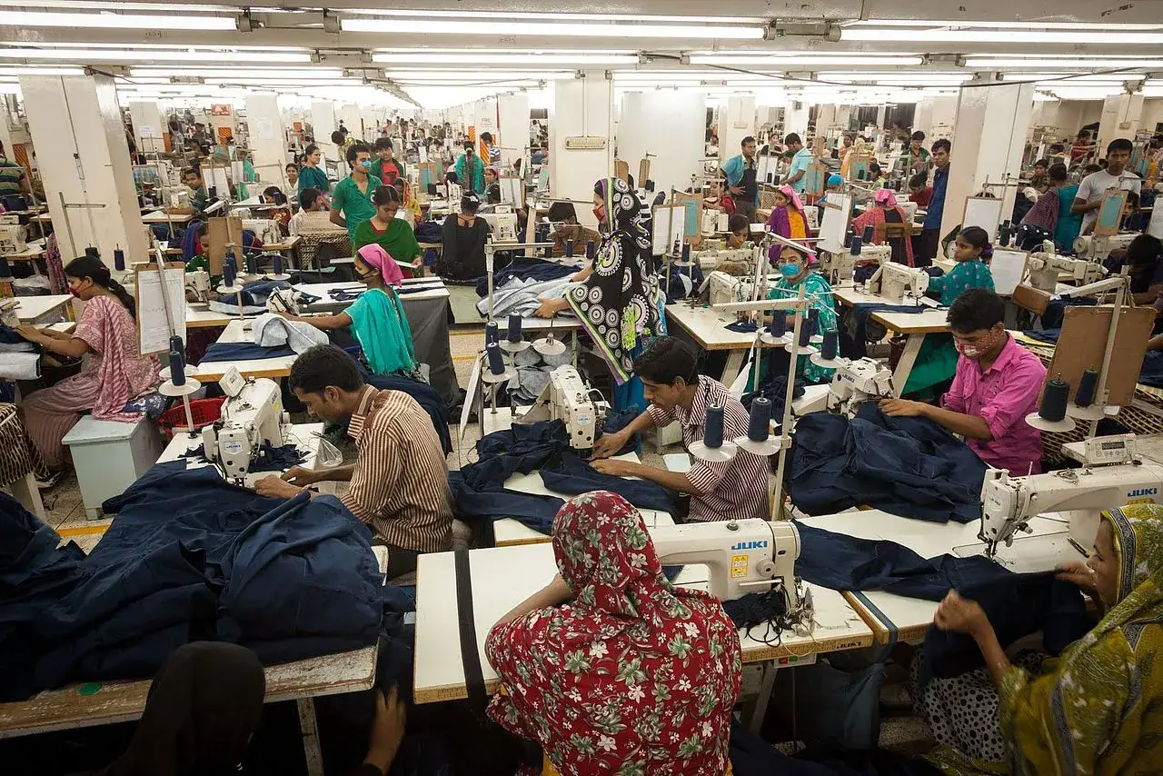 Menschen arbeiten in einer Textilfabrik, ein Beispiel f&uuml;r die Nachteile von Fast Fashion: Ausbeutung und schlechte Arbeitsbedingungen.
