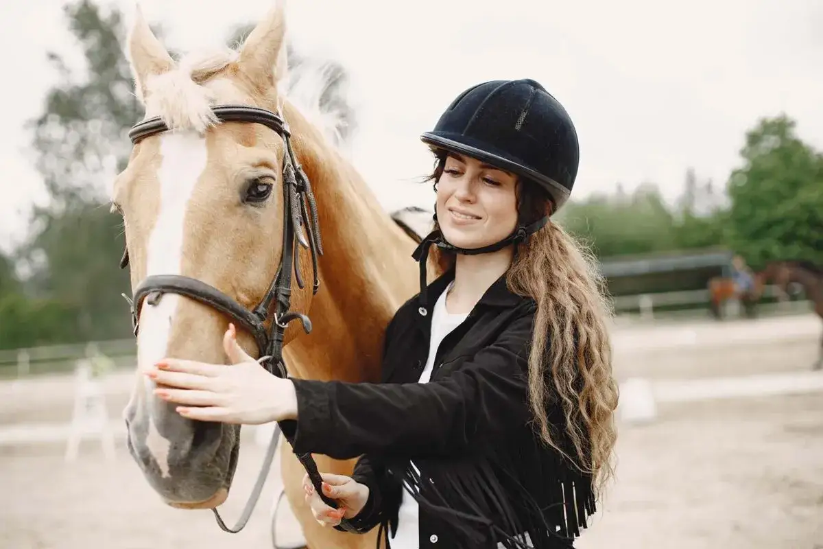 Une cavali&egrave;re souriante caresse son cheval. Quel galop pour avoir un cheval aussi beau !