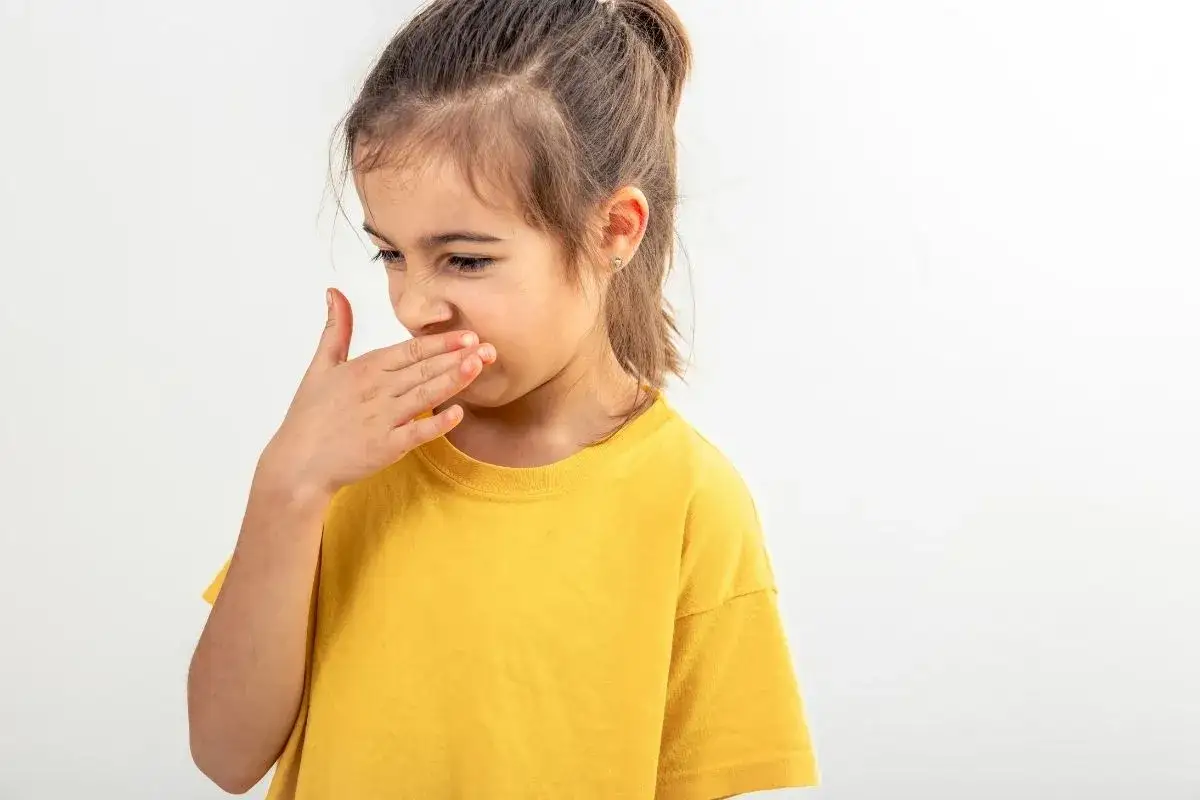 Bambina con la mano sulla bocca, espressione di disgusto, forse per l'alitosi dei bambini.