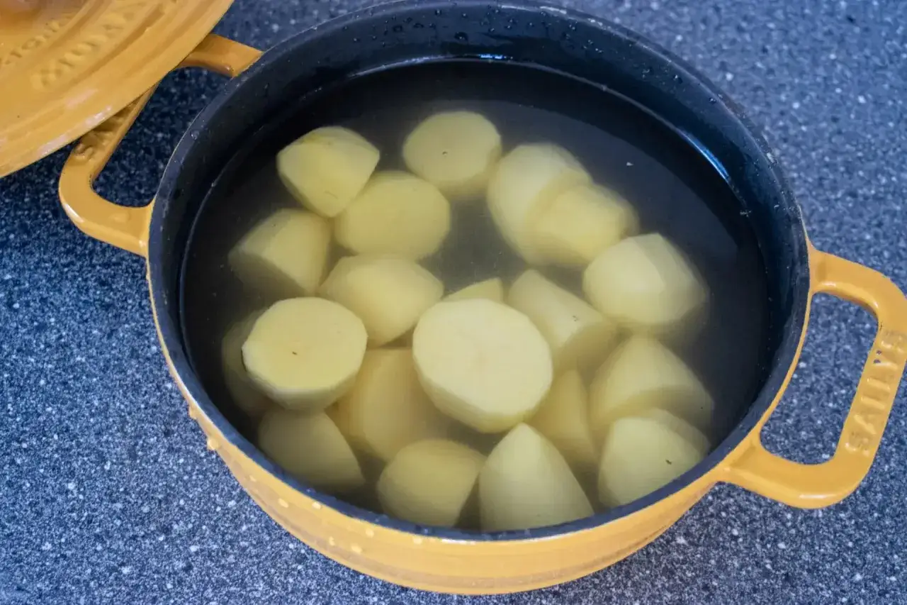 Gekochte Kartoffelst&uuml;cke in einem gelben Topf. Bald sind die Kartoffeln gar und bereit f&uuml;r die Zubereitung.