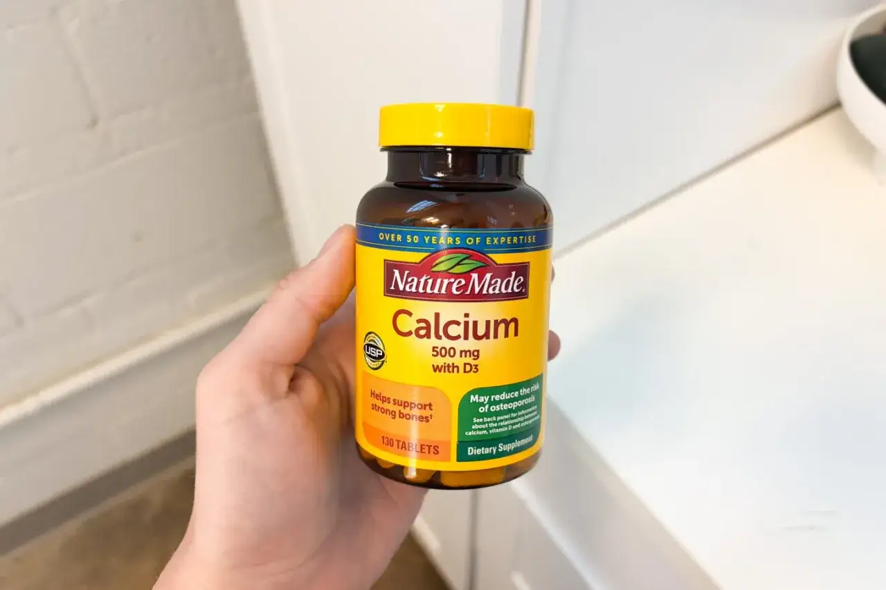 Dłoń trzyma butelkę suplementu Nature Made Calcium 500 mg z D3, który wspiera mocne kości i może zmniejszać ryzyko osteoporozy.