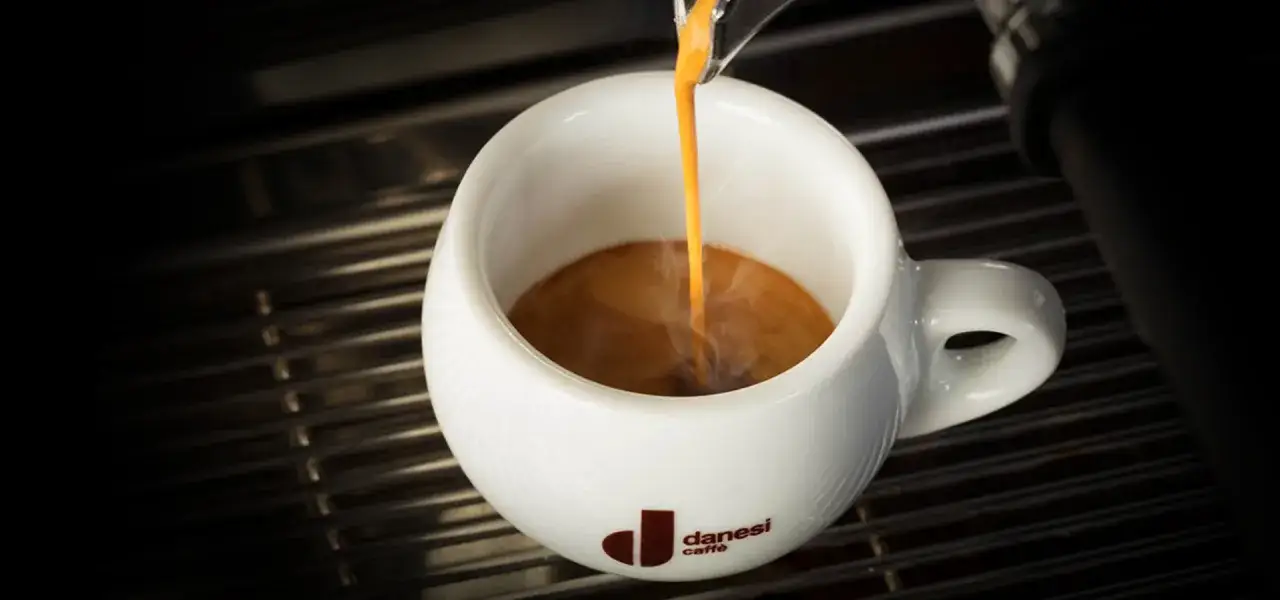 Un espresso Danesi si versa in una tazza bianca, un momento di piacere per le donne e gli amanti del caff&egrave;.