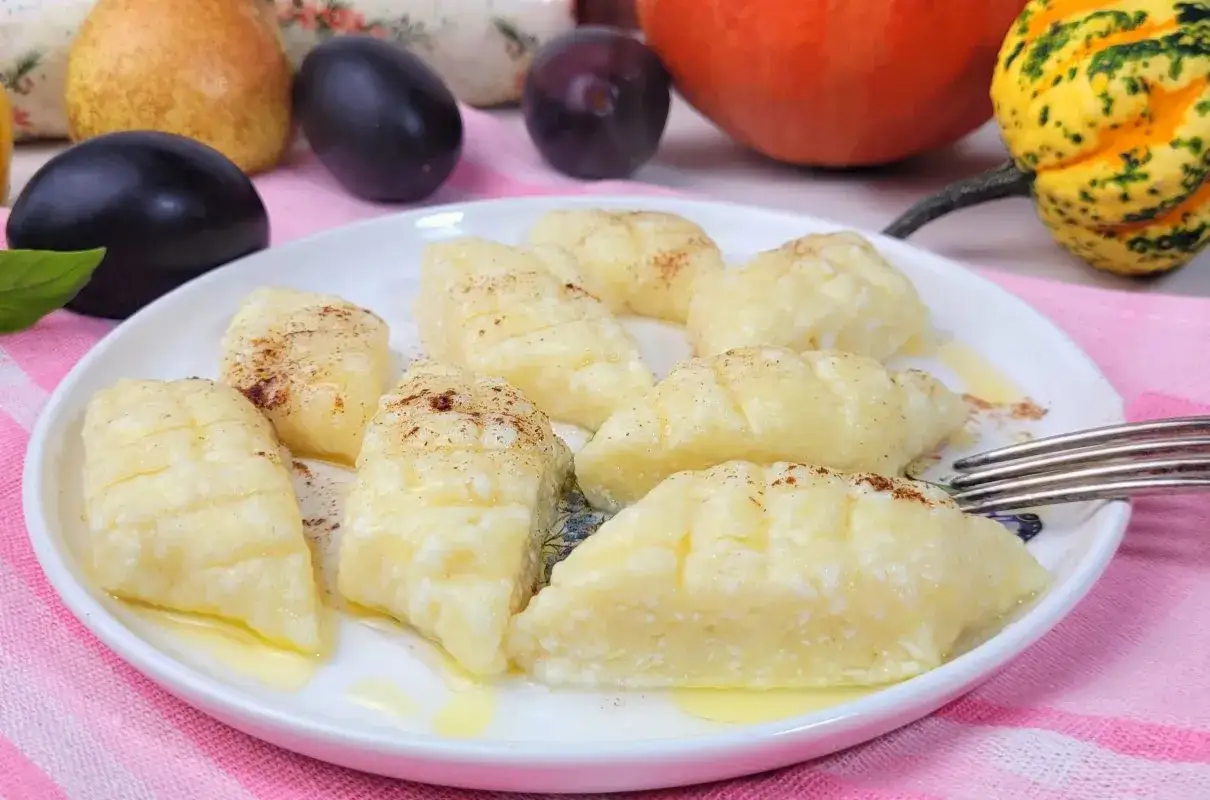 Pyszne kluski leniwe, posypane cynamonem, idealne na leniwe popołudnie. Obok śliwki, gruszka i dynie.