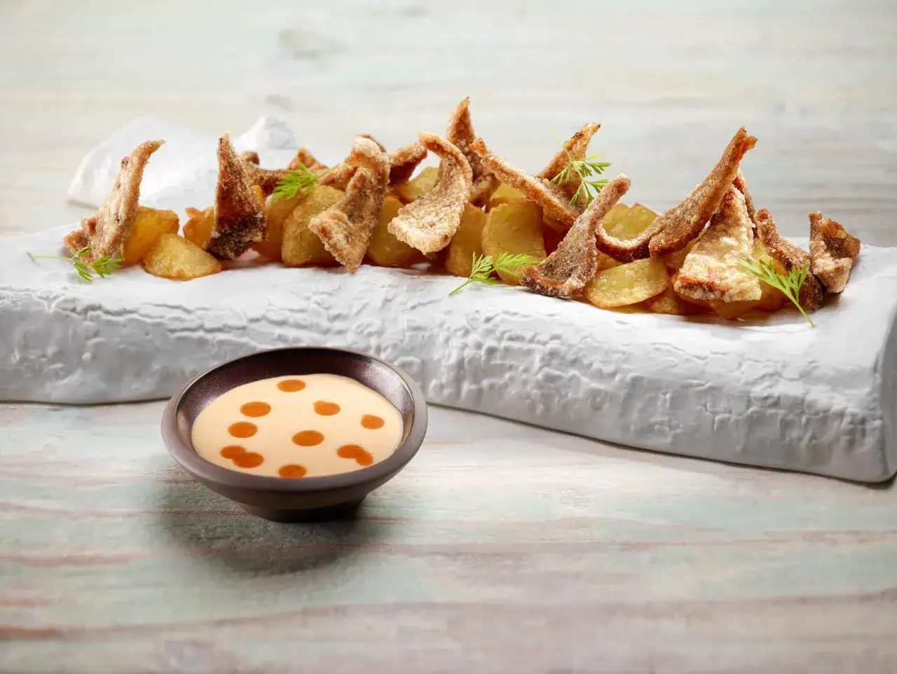 Crujiente oreja de cerdo frita con patatas y una salsa cremosa.