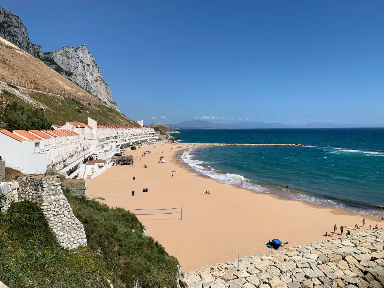 Sonniger Strand mit H&auml;usern und dem Felsen von Gibraltar im Hintergrund, Blick auf das Mittelmeer.