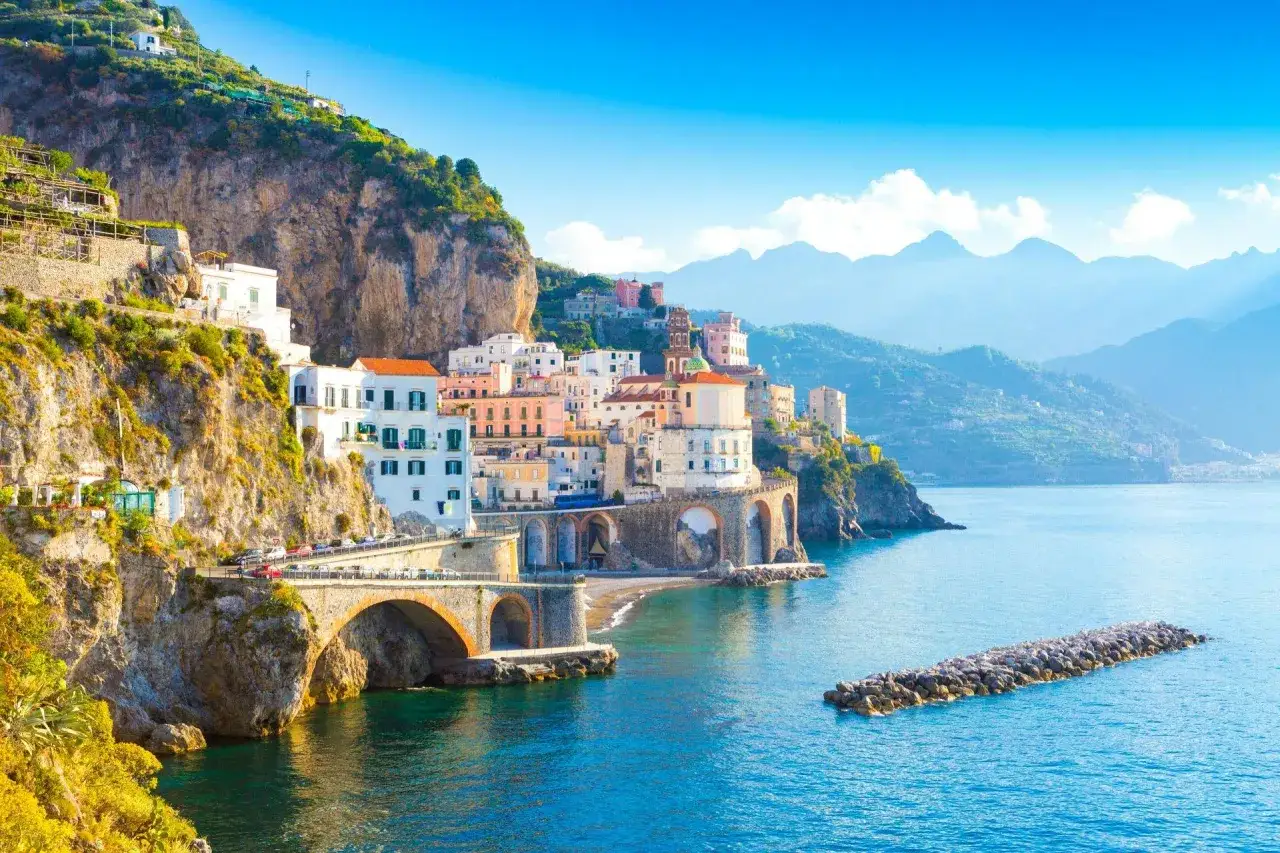 F&auml;rgstarka hus kl&auml;ttrar uppf&ouml;r klipporna vid **Sorrentohalv&ouml;n**, med broar som sp&auml;nner &ouml;ver havet.