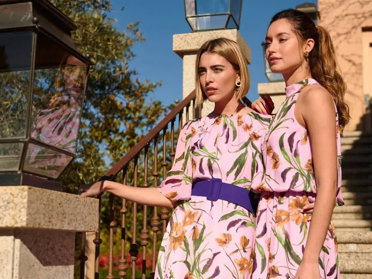 Dos mujeres con vestidos florales rosas, una con cintur&oacute;n morado, perfectas para saber como ir vestida a una boda civil de invitada.