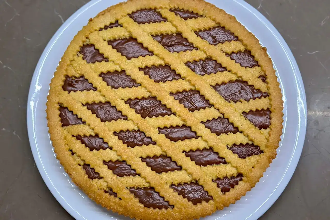 Crostata alla Nutella con una griglia di pasta frolla dorata che racchiude un ripieno goloso e cremoso.