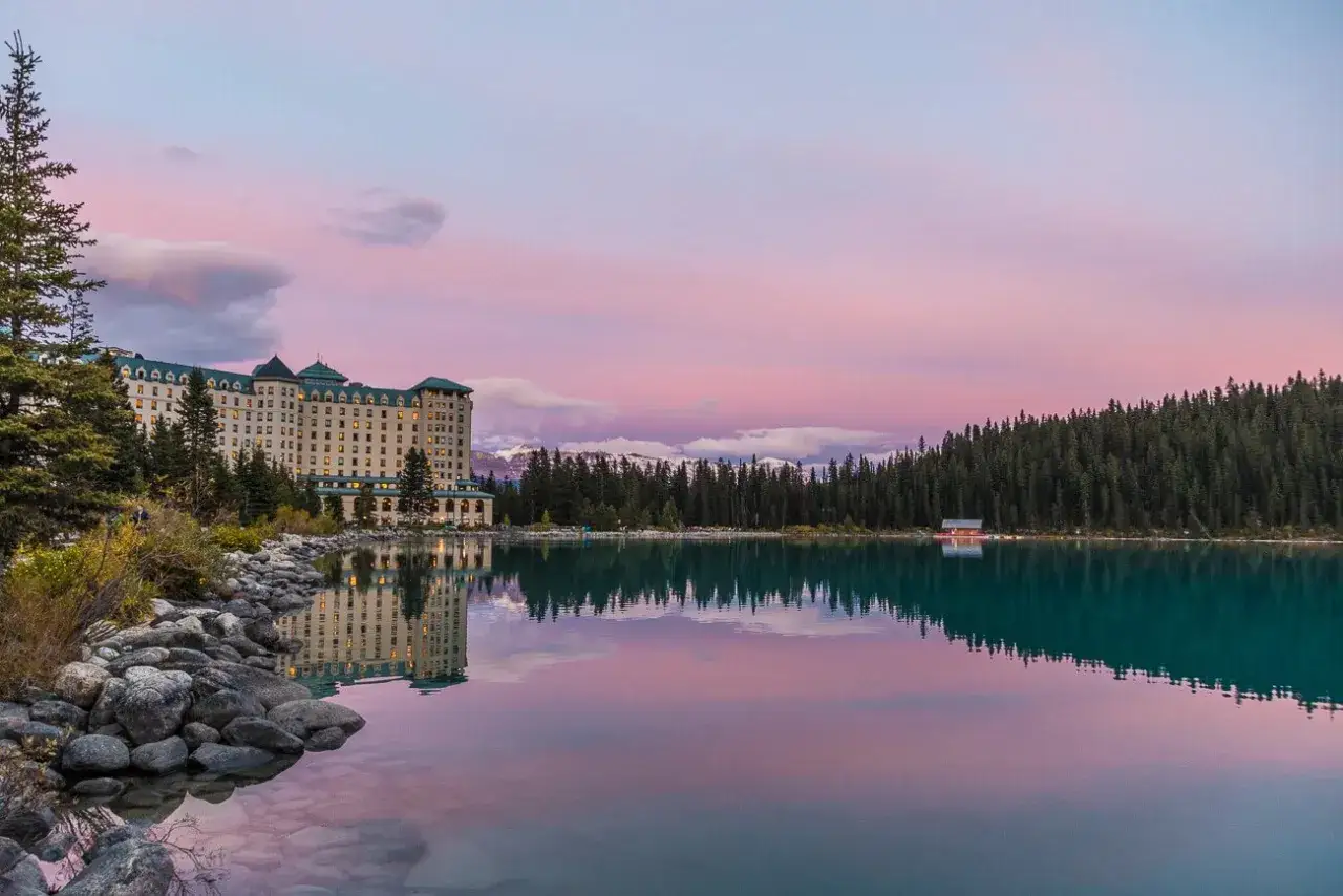 Impresionante hotel junto a un lago turquesa en Canadá, con montañas nevadas y un cielo rosado. Un lugar que ver para soñar.