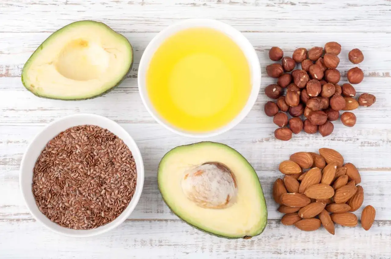 Avocado, semi di lino, olio giallo, nocciole e mandorle, ingredienti ricchi di acidi grassi essenziali per una dieta sana.