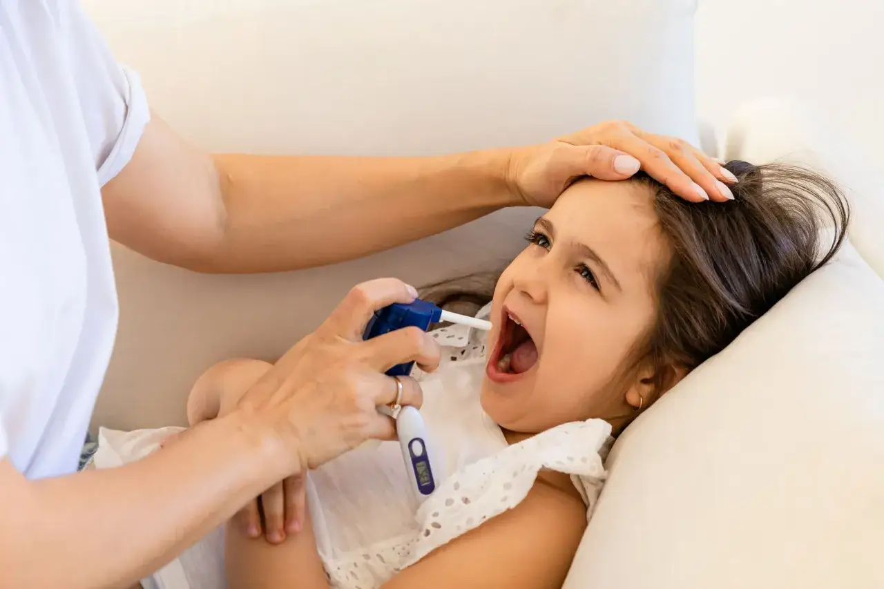 Mama podaje dziecku spray do gardła, szukając odpowiedzi, jaki syrop na kaszel krtaniowy będzie najlepszy.