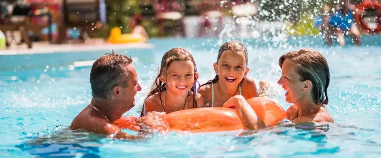 Familie planscht im Monbijou Bad, lachend auf einem orangefarbenen Schwimmring.