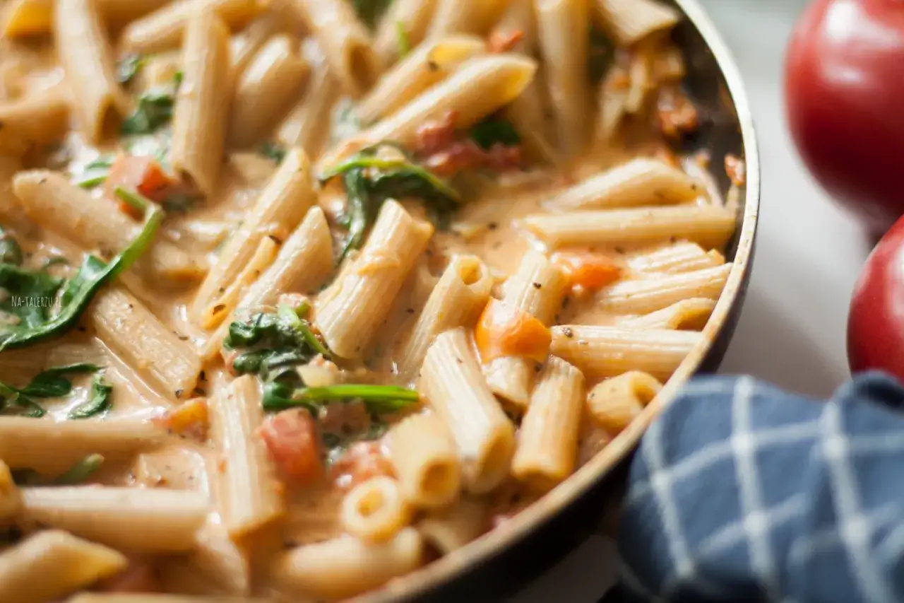 Penne alla vodka w kremowym sosie z pomidorami i szpinakiem, gotowe do podania.