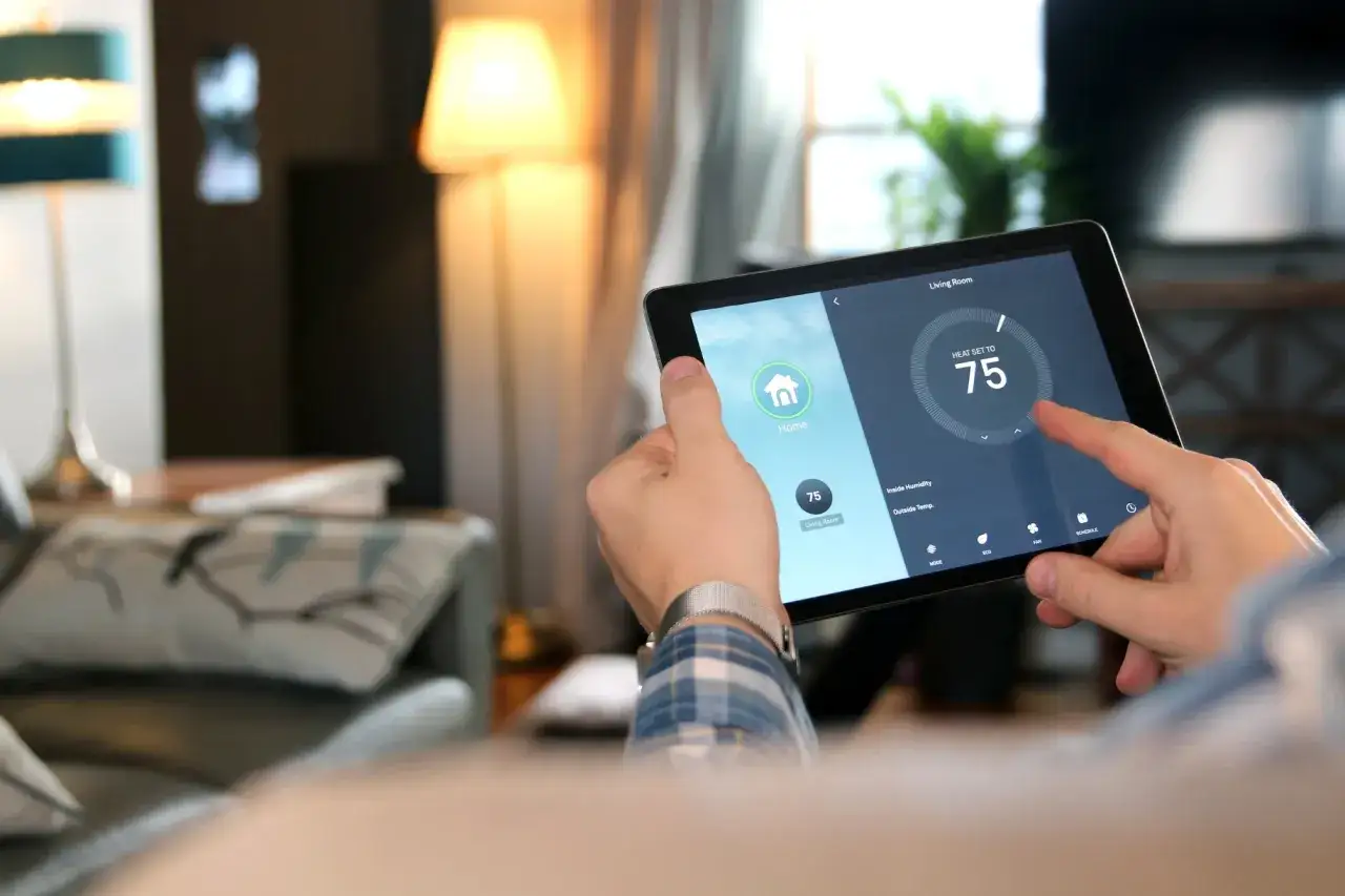 Mann stellt mit Tablet die Heizung auf 75 Grad ein. Ein gemütliches Zuhause dank smarter Technik, die wie eine homey bridge funktioniert.