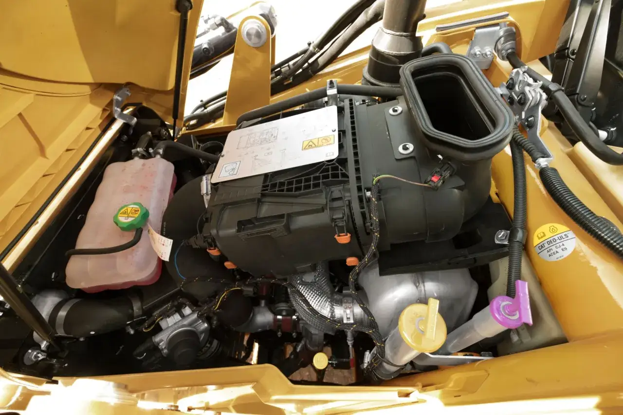Silnik CAT 428C z widocznym wlewem oleju hydraulicznego, zbiornikiem płynu chłodniczego i elementami układu dolotowego.