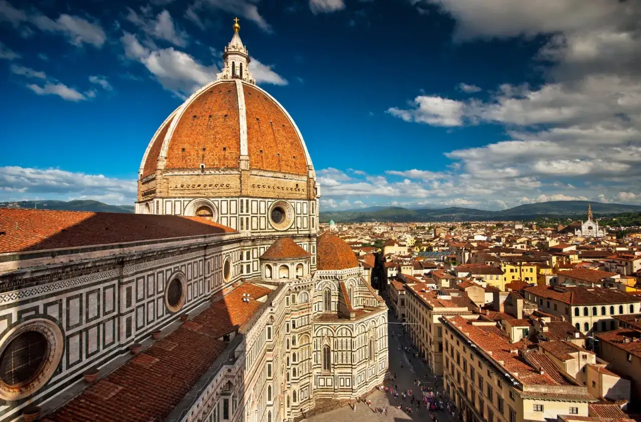 Cupola del Duomo di Firenze, un'icona per scoprire le cose da fare a Firenze. Vista panoramica sulla città con cielo azzurro e nuvole.