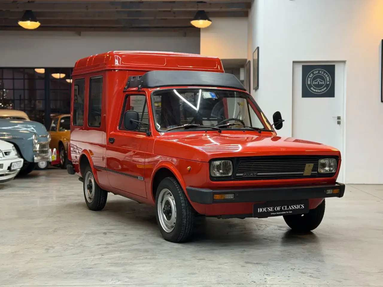 Czerwony Fiat 127 Furgon, klasyk z lat 80., prezentuje się w salonie samochodów zabytkowych.